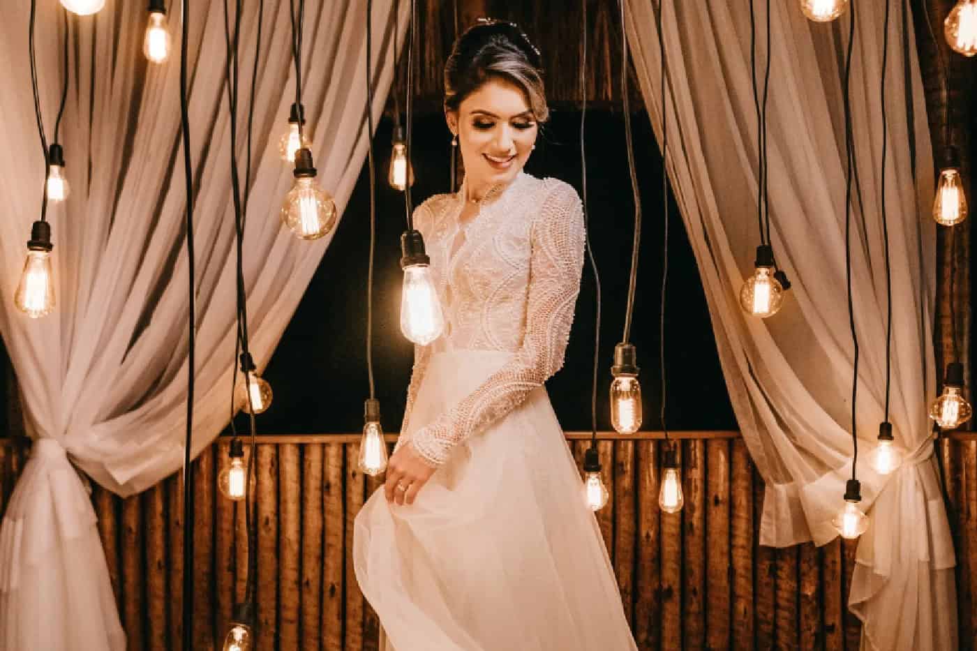 Bride dancing under warm string lights at wedding reception.